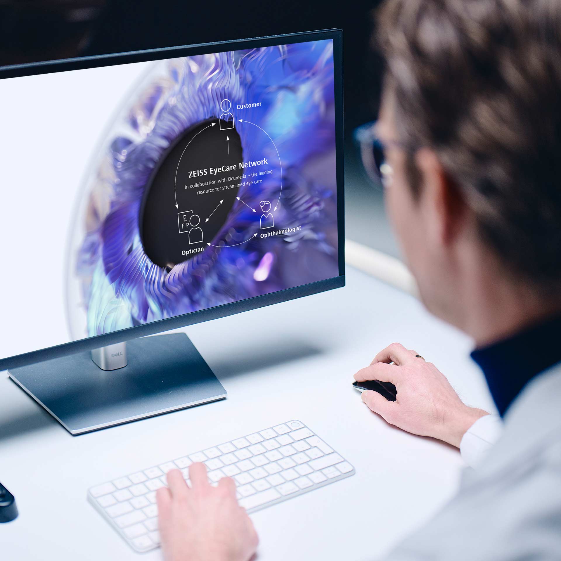 Ein Man sitzt vor einem Computer, auf dem das ZEISS EyeCare Network zu sehen ist.