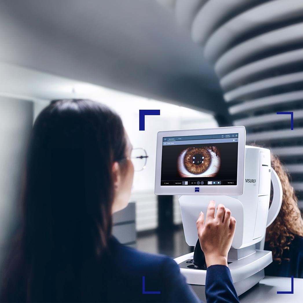 Eine Augenoptikerin schaut auf den Bildschirm eines ZEISS VISUREF 600, auf dem das Bild eines Auges zu sehen ist.