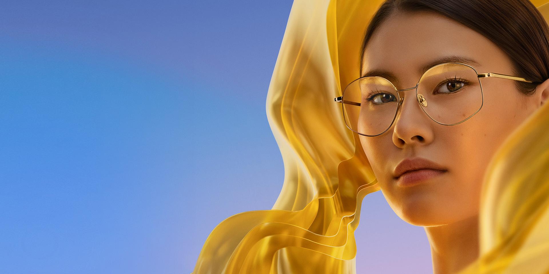 Eine Frau mit einer klaren Brille mit ZEISS DuraVision Gold UV, die den Brillengläsern einen dezenten, aber unverwechselbaren goldenen Reflex verleiht.