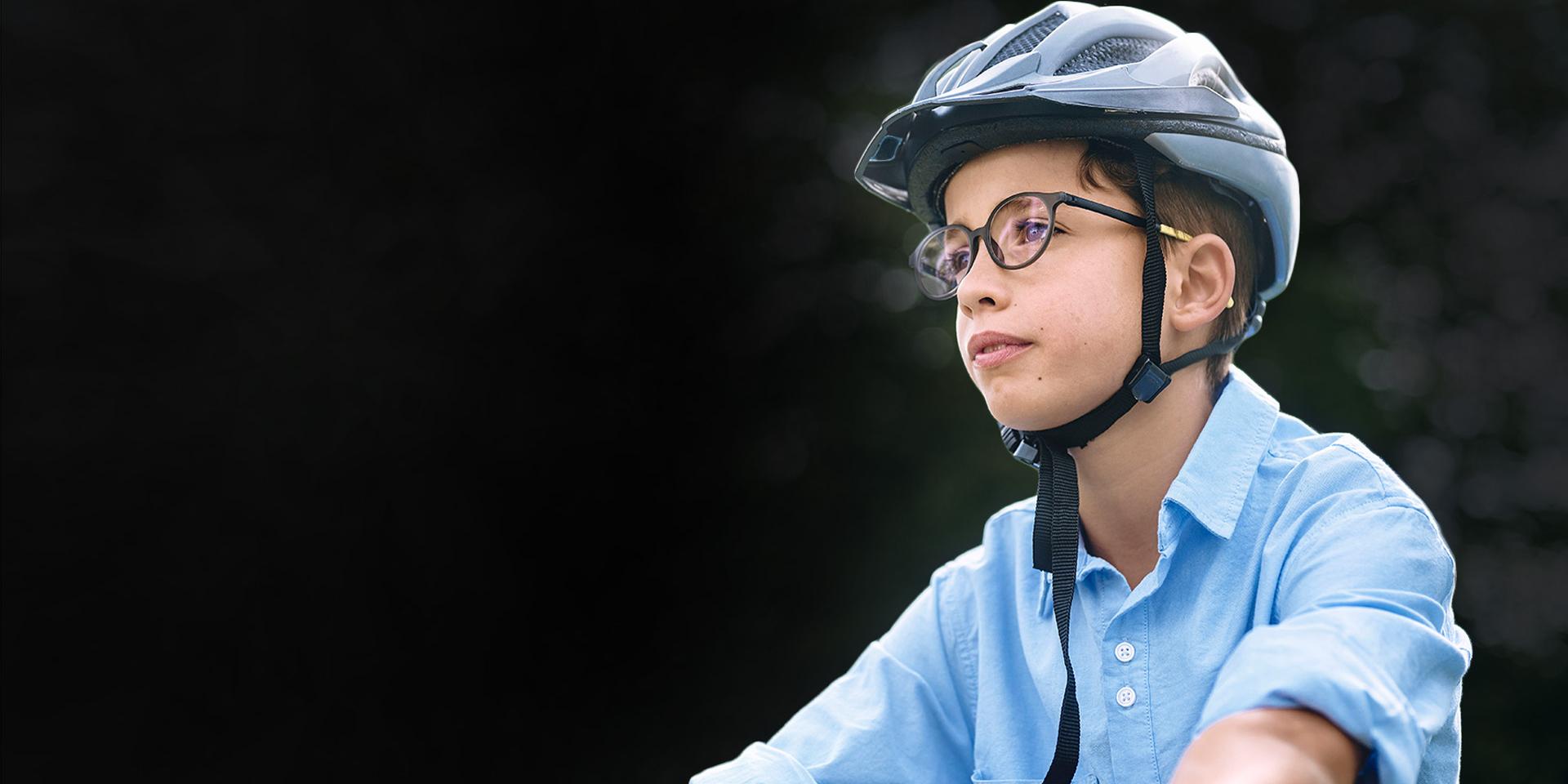 Ein kleiner Junge mit Brille und Helm fährt offenbar Fahrrad.