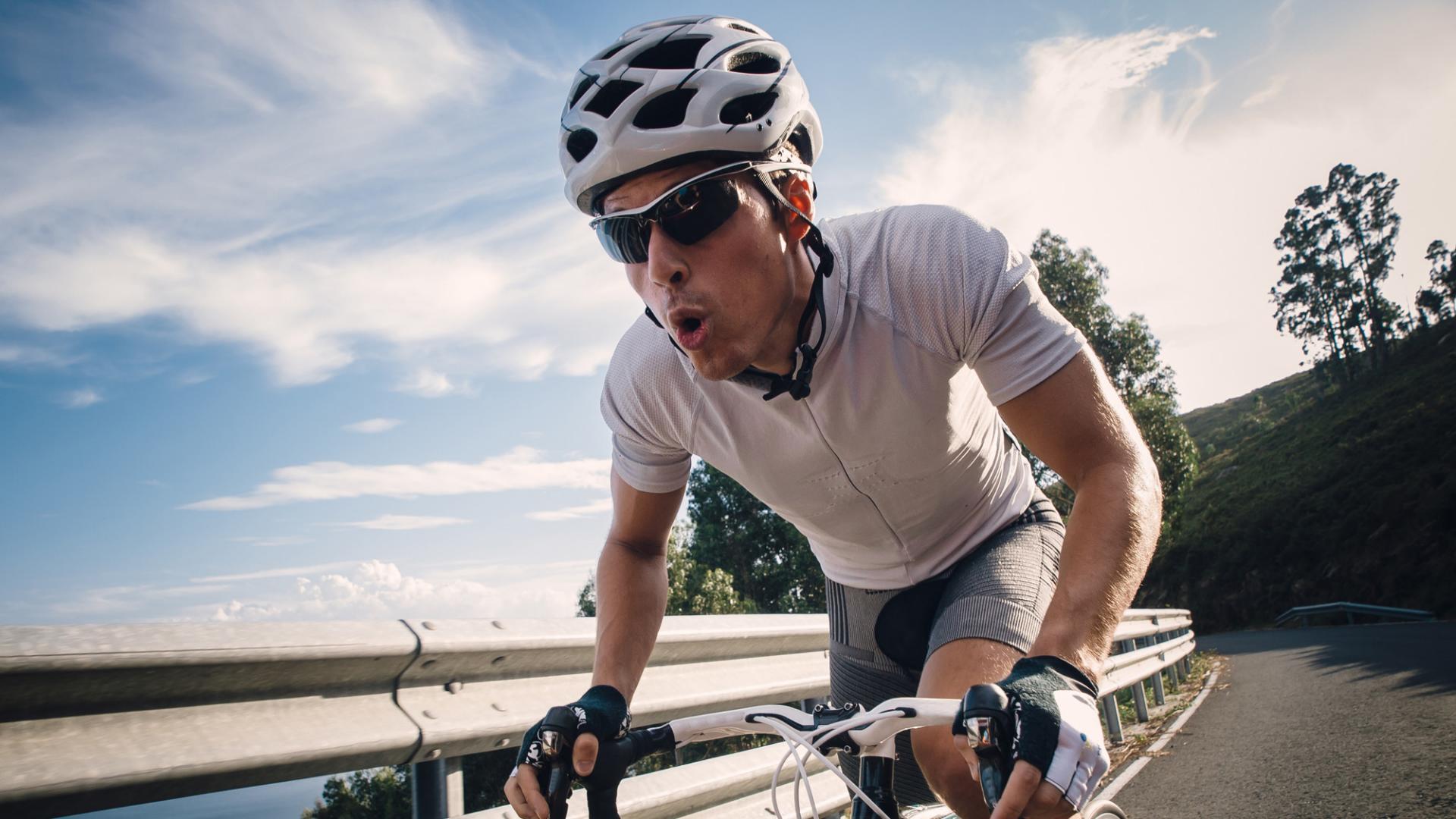 Man cycling in the road with maximum effort.