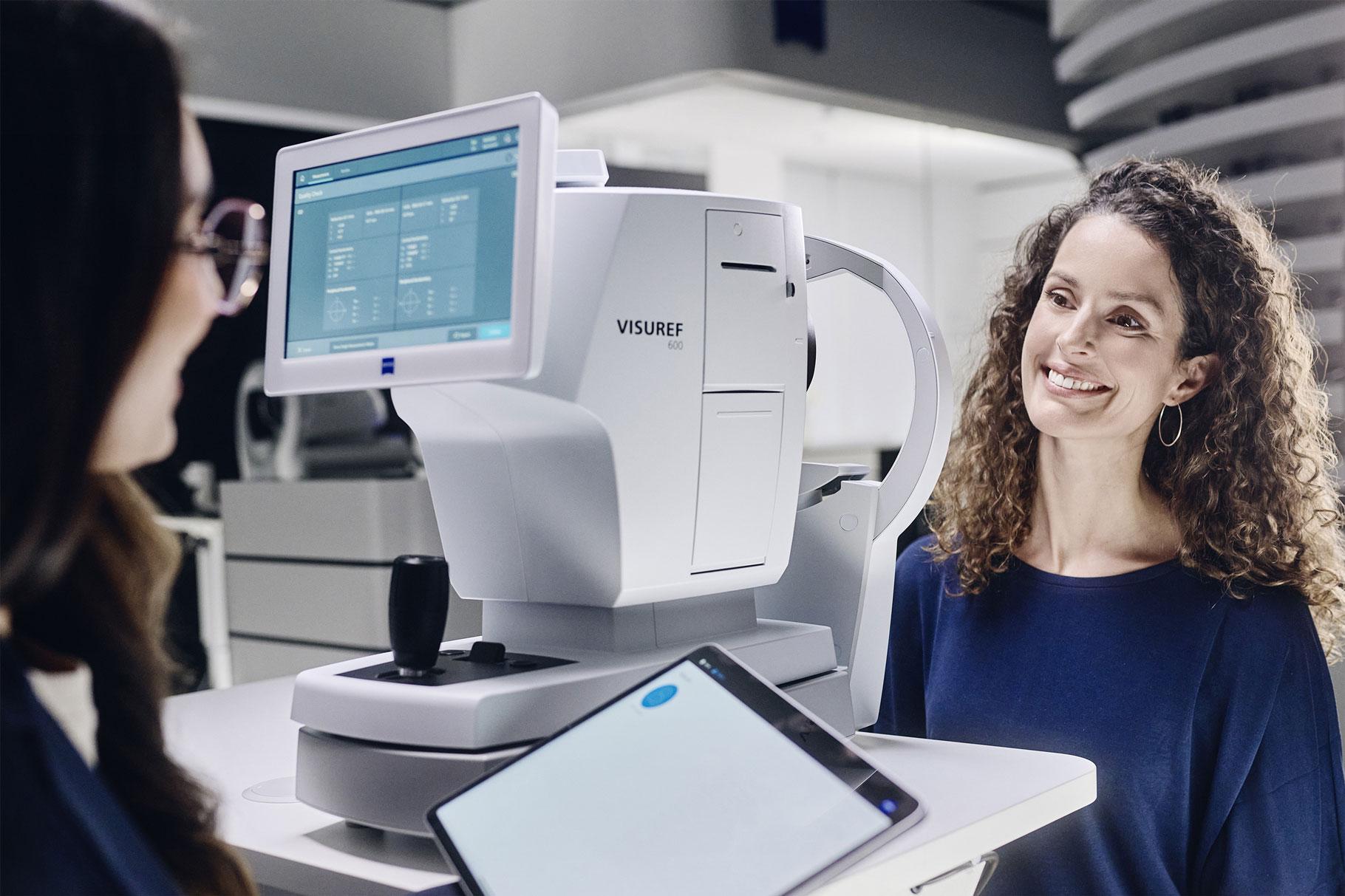 Augenoptikerin und Kundin sitzen sich am ZEISS VISUREF gegenüber.