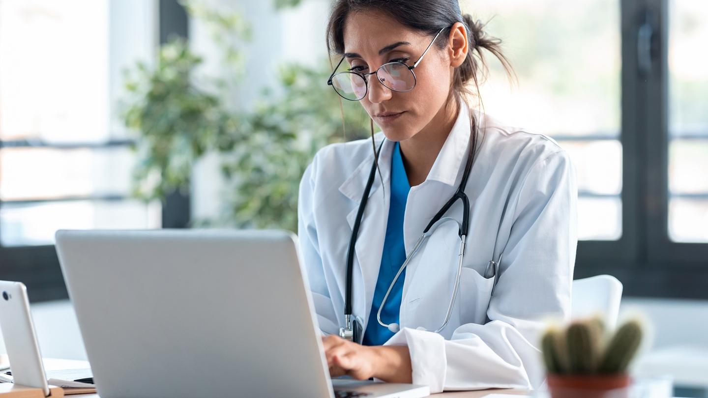 Augenärztin sitzt am Schreibtisch vor ihrem Laptop