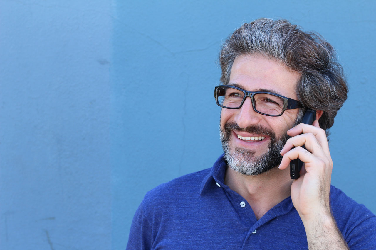 Ein Mann mit Brille telefoniert mit einem Handy