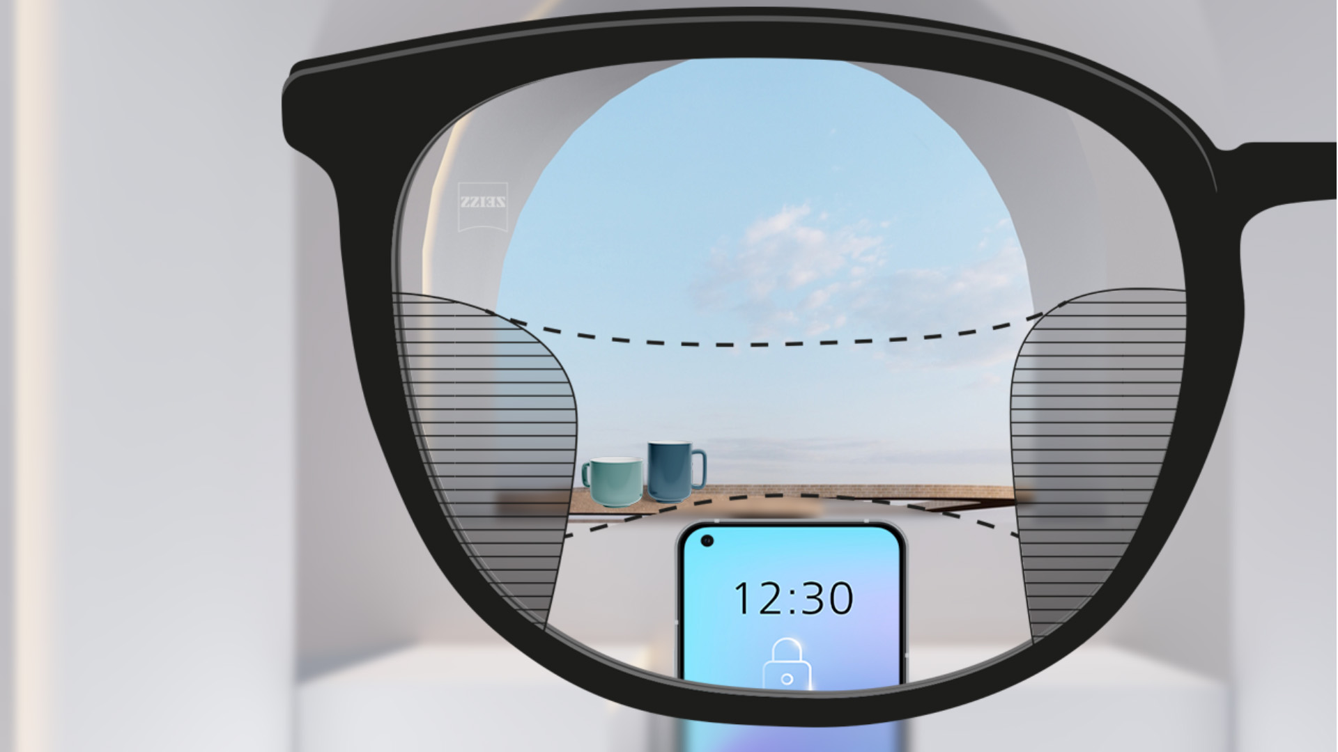 Abbildung mit Blick durch ein ZEISS SmartLife Gleitsichtglas. Ein Smartphone ist zu sehen, und im Hintergrund Tassen. Das Brillenglas ist vollkommen klar, mit geringen unscharfen Flächen links und rechts.