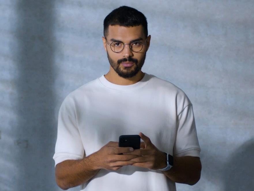 Ein junger Mann mit ZEISS BlueGuard Brille beschäftigt sich mit seinem Smartphone.
