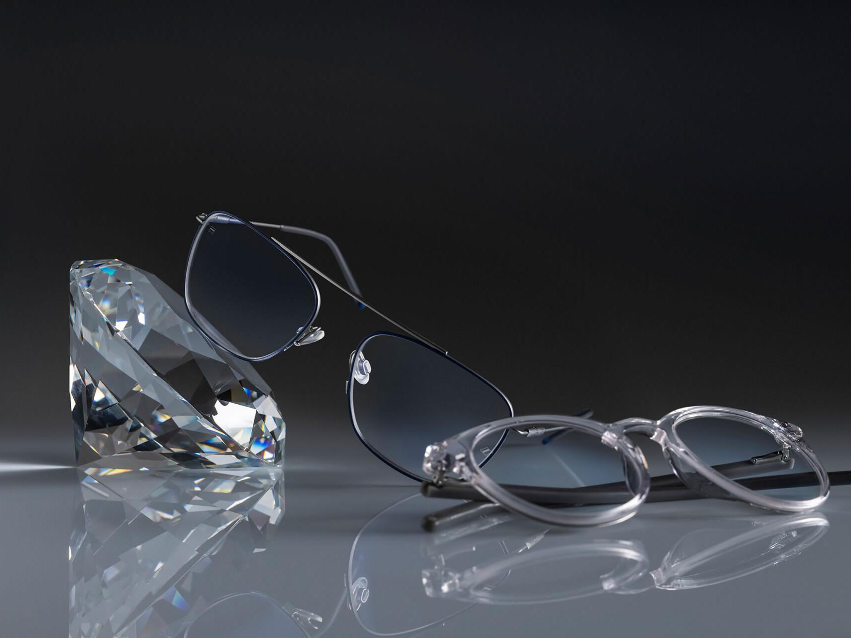 Zwei Brillen mit ZEISS Brillengläsern und der härtesten ZEISS Beschichtung aller Zeiten – DuraVision® Platinum. Eine Brille ist an einen Kristall angelehnt, die andere liegt flach auf dem Boden. Bei beiden sind die Brillengläser absolut klar, ohne bläuliche Reflexionen.