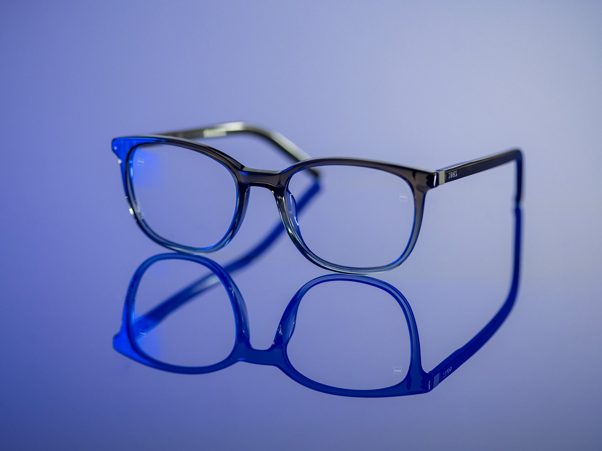 In einem bläulichen Licht sind Brillen mit ZEISS Brillengläsern mit BlueGuard-Brillenglasmaterial zu sehen. Auf den Brillengläsern sind nur sehr geringe bläuliche Reflexionen sichtbar.