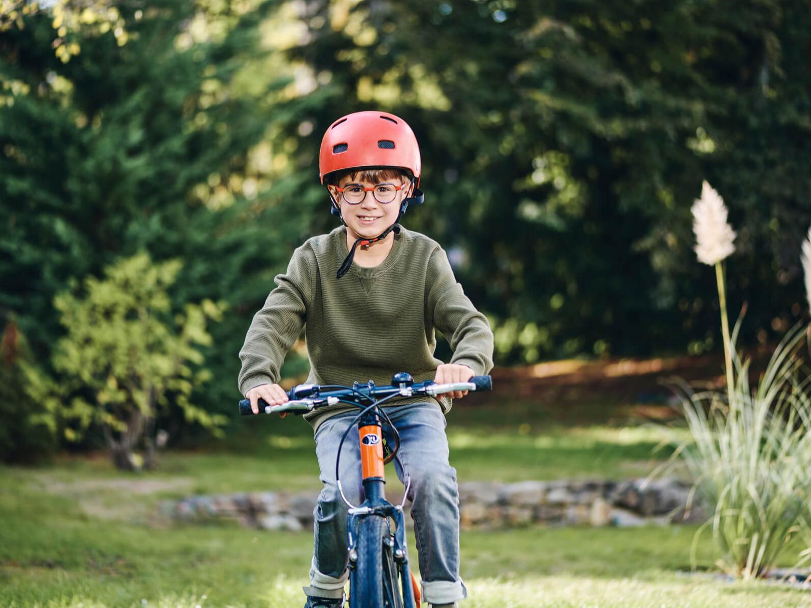 Ein kleiner Junge im Freien mit Fahrrad trägt Brillengläser für die Myopie-Behandlung von ZEISS.