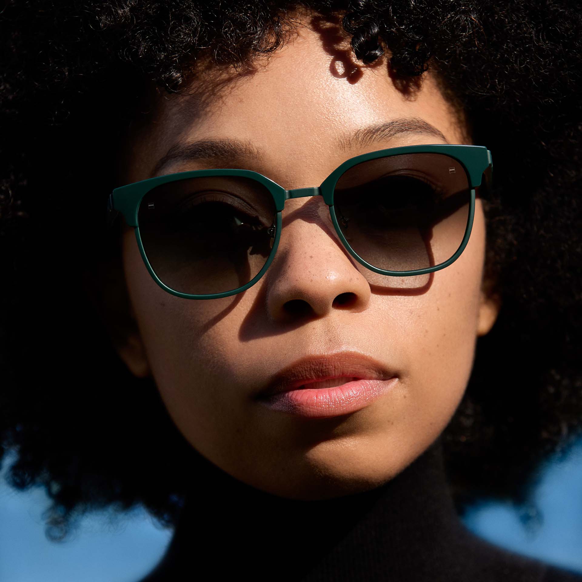 Eine Frau trägt eine Brille mit grüner Fassung und Gläsern mit einer Verlaufstönung. 