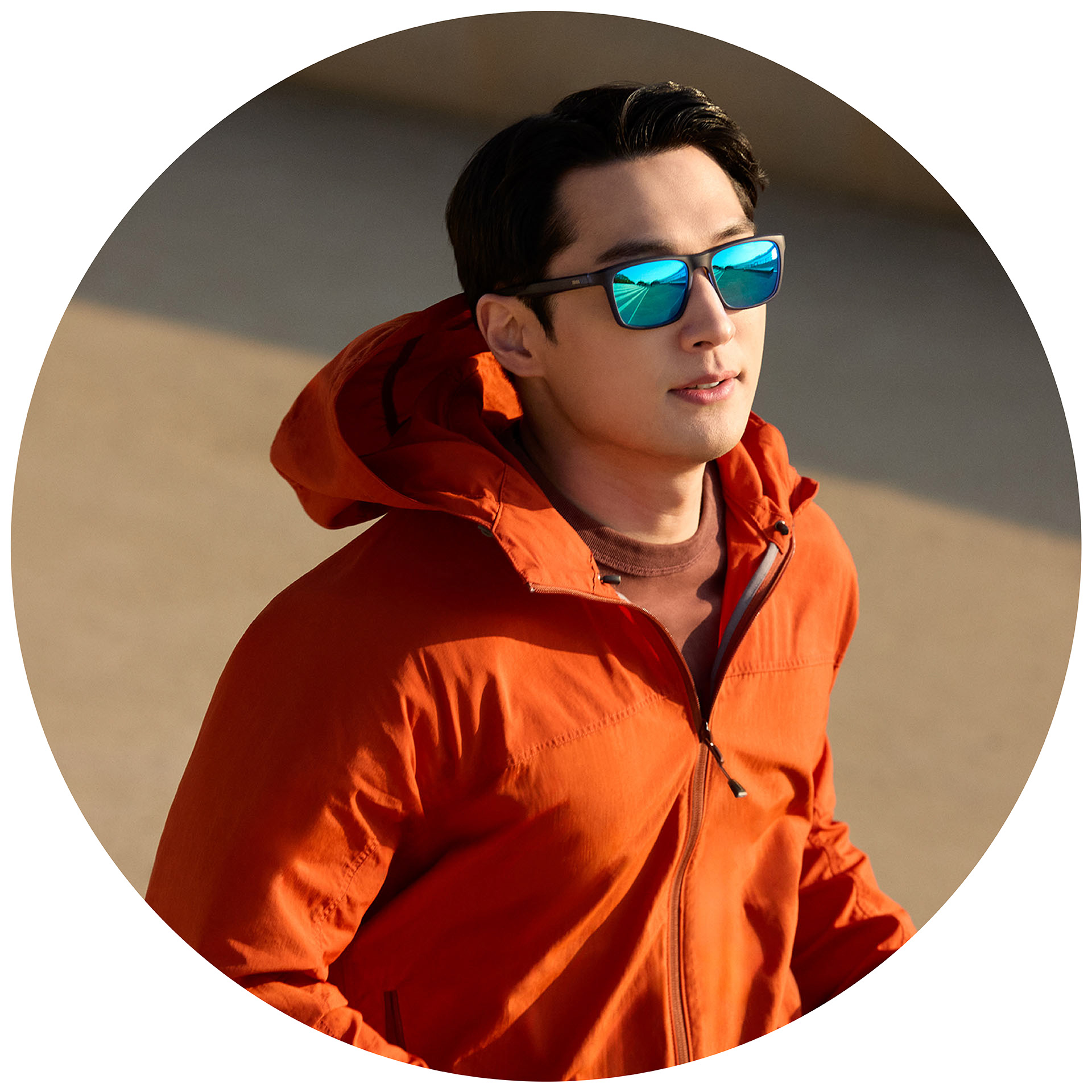 Ein Jogger in einer orangen Jacke trägt eine ZEISS Sonnenbrille mit Sehstärke mit einer blauen Spiegelbeschichtung.