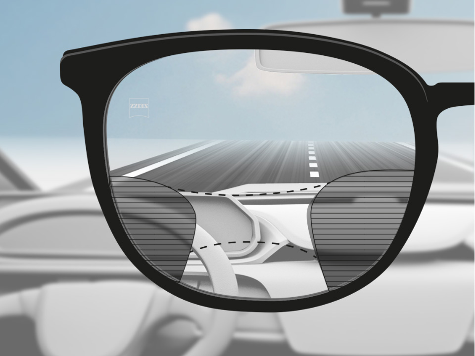 Abbildung mit Blick aus der Perspektive eines Autofahrers durch ein ZEISS DriveSafe Gleitsichtglas mit scharfer Sicht auf die Straße und das Armaturenbrett und unscharfen Flächen links und rechts. 