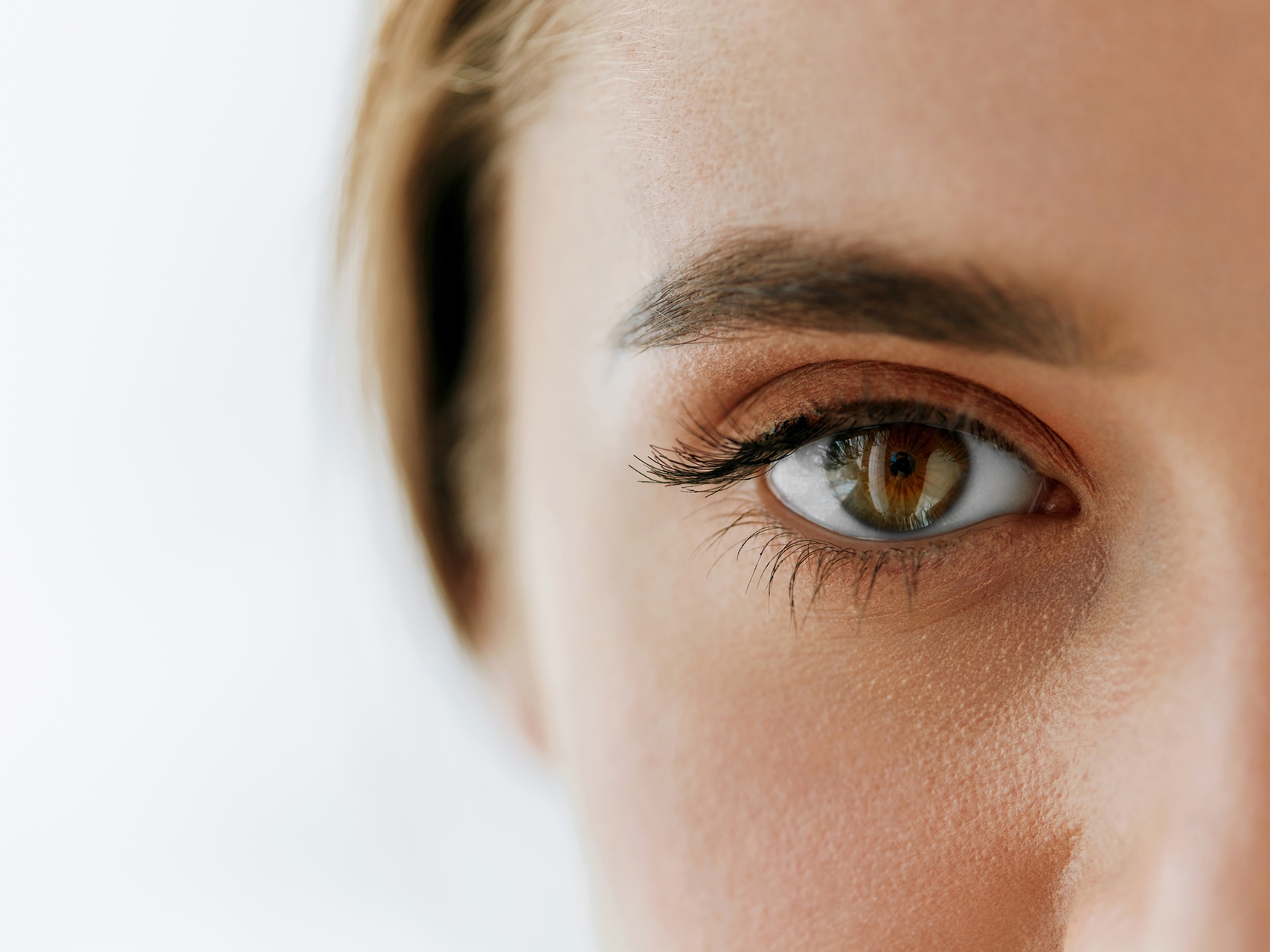Das Bild zeigt eine Nahaufnahme des Gesichts einer Frau, wobei der Fokus auf dem linken Auge liegt. 