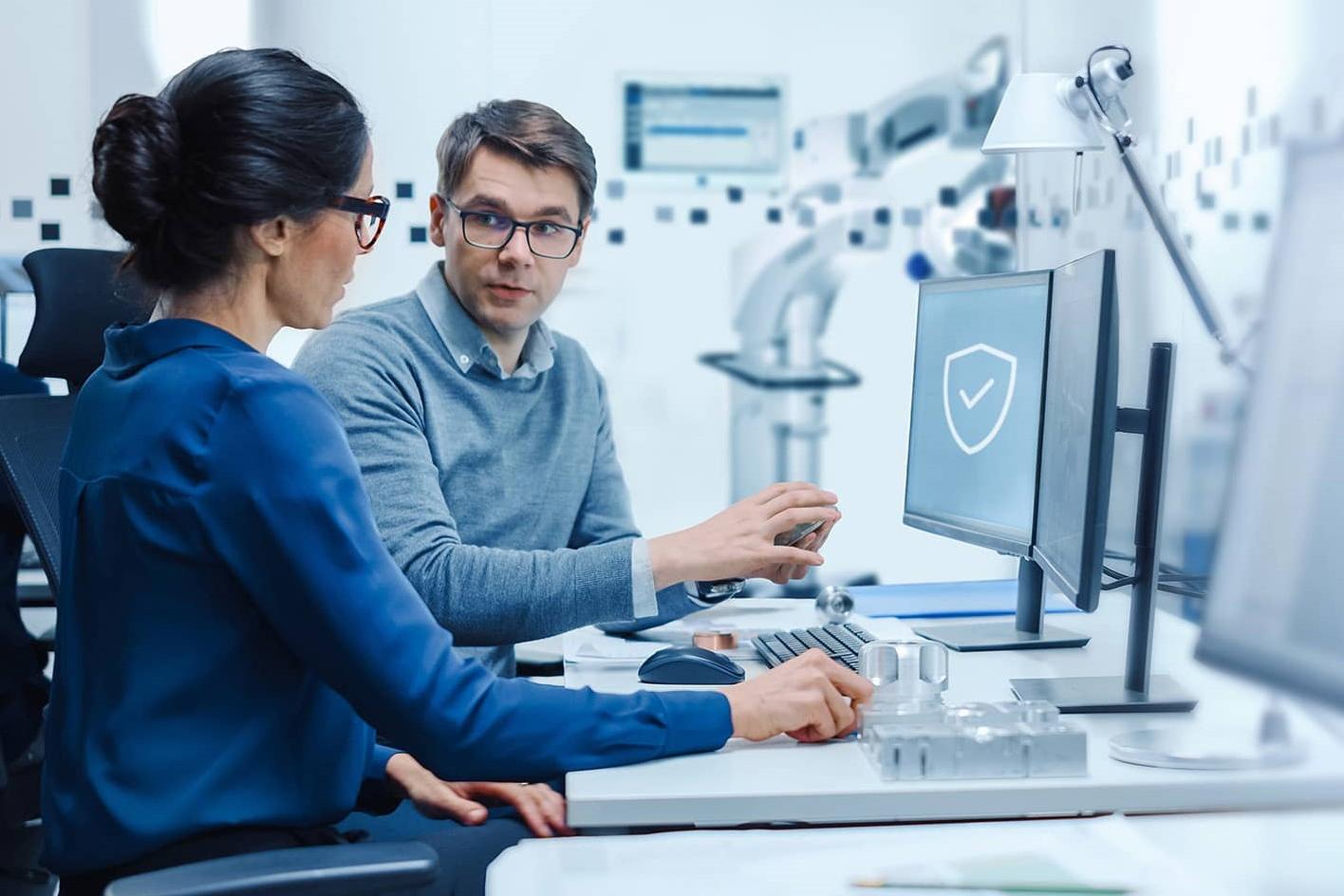 Zwei Fachleute besprechen die Arbeit an einem Computerarbeitsplatz in einer Hightech-Umgebung des Labors.