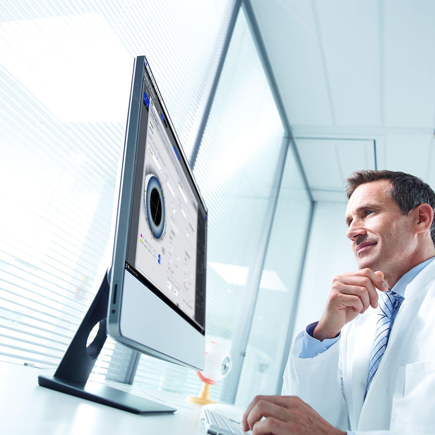 Ein Mann im Laborkittel schaut auf einen Bildschirm, auf dem eine Software zur Augenmessung angezeigt wird. 