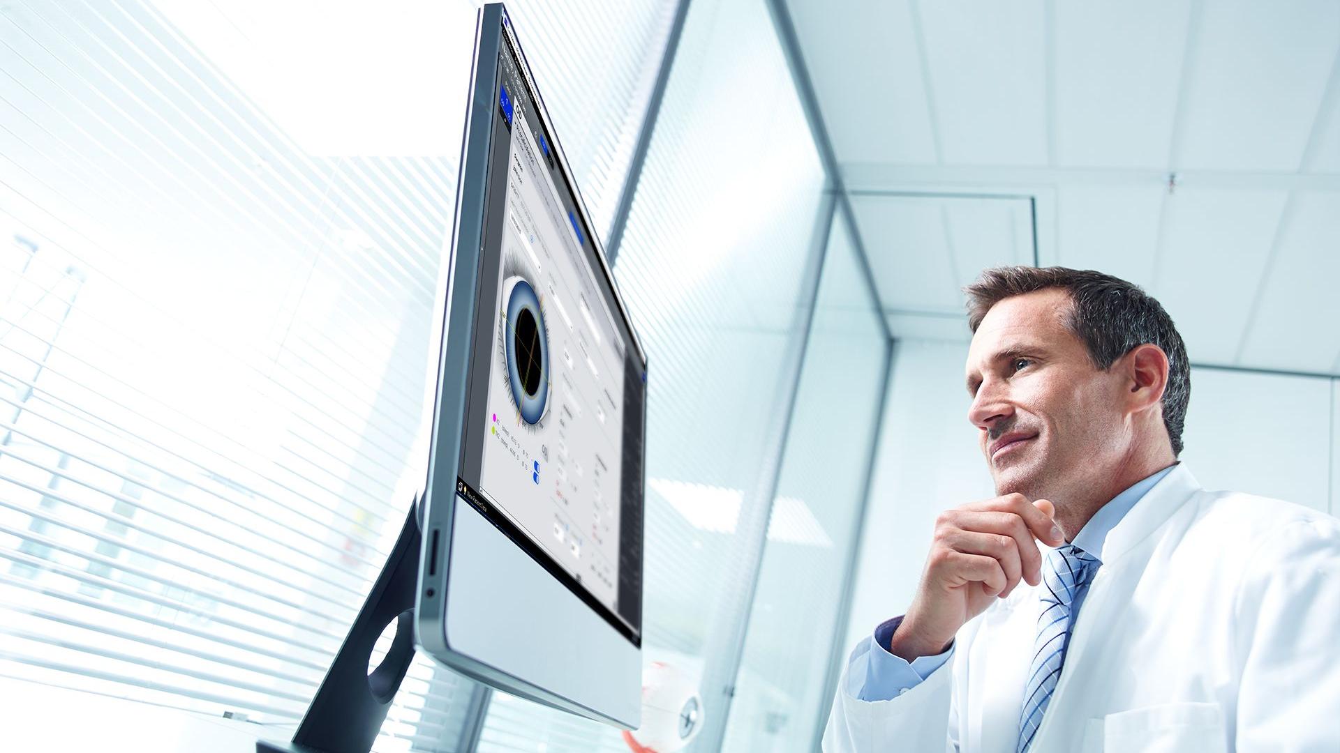 Mann im Kittel vor Monitor mit Augenvermessungssoftware. 